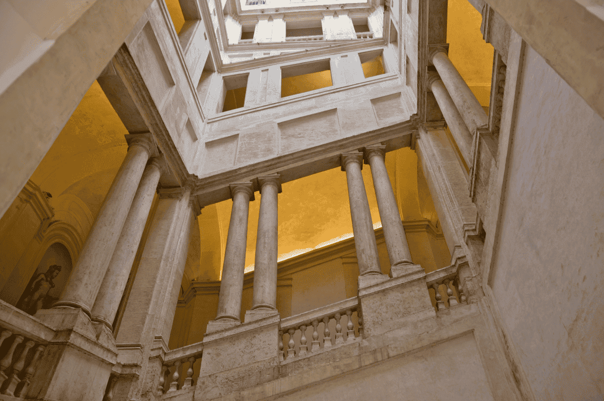 Vista interior de una escalera histórica con columnas.